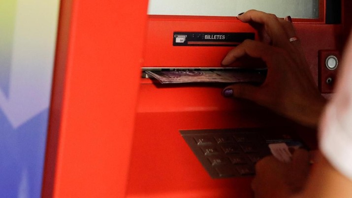 Seorang wanita menerima catatan Bolivar dari mesin kasir otomatis (ATM) di Caracas, Venezuela 23 Maret 2018. REUTERS / Marco Bello