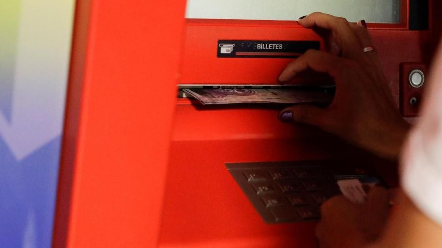 Seorang wanita menerima catatan Bolivar dari mesin kasir otomatis (ATM) di Caracas, Venezuela 23 Maret 2018. REUTERS / Marco Bello
