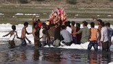Sementara itu, patung besar Dewa Durga dilarung di sungai yang penuh busa itu. (REUTERS/Adnan Abidi)