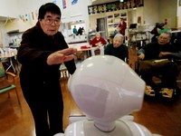 Seorang warga mendekati robot humanoid 'Pepper' untuk menepuk kepalanya selama rutinitas latihan sore di rumah perawatan Shin-tomi di Tokyo, Jepang, 2 Februari 2018. REUTERS / Kim Kyung-Hoon
