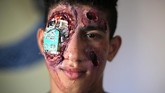 Lelaki lainnya lagi ia lukis dengan ‘mesin’ yang mirip. Namun, mesin itu tidak diletakkan di tengah dada, melainkan di salah satu matanya. (REUTERS/Ibraheem Abu Mustafa)