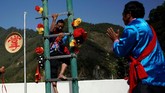Atraksi paling populer dan mencekam adalah memanjat sebuah galah setinggi 20 meter dengan 36 bilah pisau tajam yang dipasang berderet di antara dua galah sehingga menyerupai tangga. (REUTERS/Aly Song)