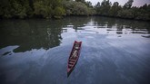 Perahu mengapung di atas air berwarna hitam karena terkontaminasi tumpahan minyak di hutan bakau di desa Kariangau, Teluk Balikpapan, Kalimantan Timur. Tumpahan minyak disebabkan kebocoran dari pipa minyak Pertamina. (Greenpeace / Jurnasyanto Sukarno)
