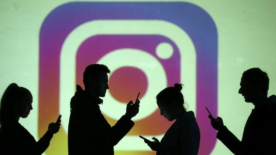 REFILE - CLARIFYING CAPTION Silhouettes of mobile users are seen next to a screen projection of Instagram logo in this picture illustration taken March 28, 2018.  REUTERS/Dado Ruvic/Illustration