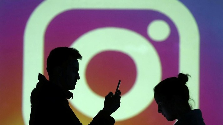 REFILE - CLARIFYING CAPTION Silhouettes of mobile users are seen next to a screen projection of Instagram logo in this picture illustration taken March 28, 2018.  REUTERS/Dado Ruvic