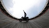 Seorang aktor pemeran penganti beraksi di atas motor di dalam arena
