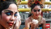 Mereka yang lelah dan butuh beristirahat duduk ala kadarnya di pinggir jalan, demi memamerkan tarian Bali yang atraktif dengan busana warna mencolok, biru dan merah. (CNN Indonesia/Andry Novelino)