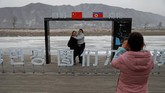 Warga berpose dengan latar belakang Korut di Tumen, China. Di Kota Dandong, tanda yang menunjukkan Korea Utara dapat ditemukan di mana-mana. (REUTERS/Damir Sagolj)