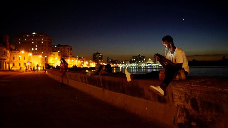 Ballet dancer Sandro Calderon, 30, connects to the internet with his mobile at a hotspot in the seafront in Havana, Cuba, April 9, 2018. Picture taken on April 9, 2018. REUTERS/Alexandre Meneghini