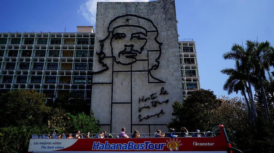 Tourists enjoy a ride on a double decker bus as they pass by a sculpture depicting revolutionary leader Che Guevara in Havana, Cuba, April 12, 2018. Picture taken on April 12, 2018. REUTERS/Alexandre Meneghini