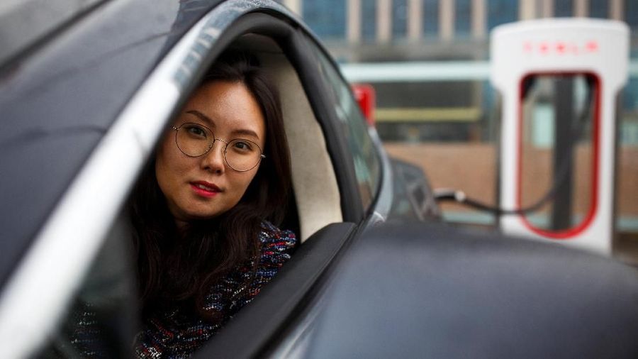 Zang Yi berpose untuk gambar saat mobil Tesla-nya sedang mengisi di titik pengisian daya di Beijing, China, 13 April 2018. Zang mengatakan jika ketegangan perdagangan menghasilkan impor AS yang lebih mahal, dia tidak akan mempertimbangkan merek Amerika ketika saatnya tiba. membeli sebuah mobil baru.