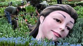 Menggunakan rangkaian bunga-bunga tulip, seorang pekerja sedang menyelesaikan instalasi seni berupa kepala raksasa di kubah Gardens by the Bay di Singapura, jelang dibukanya festival tahunan bunga tulip di sana. (AFP PHOTO / Roslan RAHMAN).