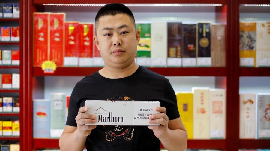 Shan Yuliang, penjual di sebuah toko rokok dan anggur, berpose dengan sekotak rokok Marlboro di Beijing, China, 8 April 2018.