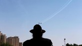 Seorang penganut agama Yahudi Ultra Ortodoks memandang pasukan udara Israel yang sedang latihan terbang akrobat jelang pertunjukan udara di hari kemerdekaan Israel ke-70, di Yerusalem. (REUTERS/Ammar Awad)