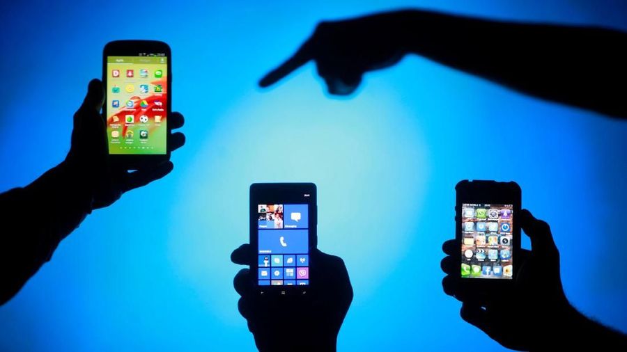 FILE PHOTO: Men are silhouetted against a video screen as they pose with smartphones in this photo illustration May 17, 2013. REUTERS/Dado Ruvic/File Photo