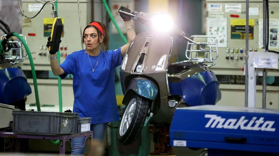 An assembly worker works on partially assembled Piaggio's Vespa at the Pontedera's farm, Italy, April 19, 2018. REUTERS/Alessandro Bianchi