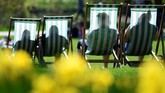 Bayangan orang yang sedang menikmati sinar matahari terlihat dari balik kursi santai di taman St. James di London, Inggris. (REUTERS/Toby Melville)