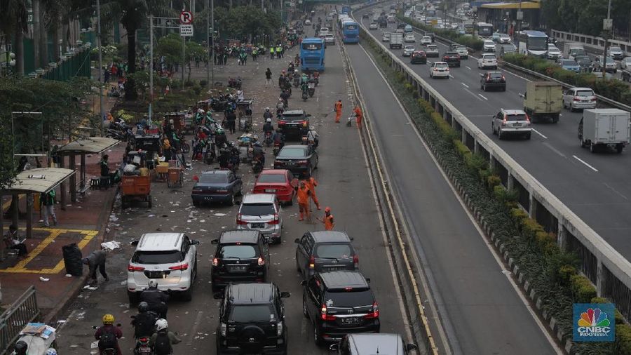 Para pasukan orange membersihkan sampah yang berserakan di jalanan usai para pendemo membubarkan diri.