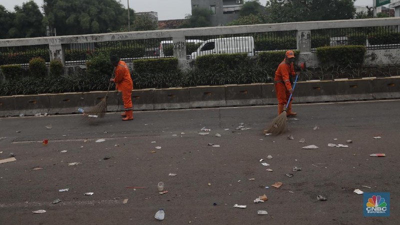 Para pasukan orange membersihkan sampah yang berserakan di jalanan usai para pendemo membubarkan diri.
