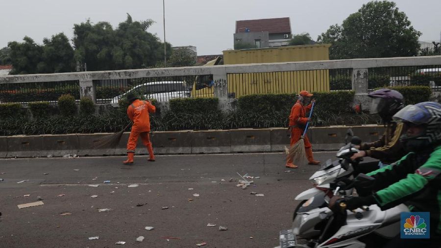 Para pasukan orange membersihkan sampah yang berserakan di jalanan usai para pendemo membubarkan diri.