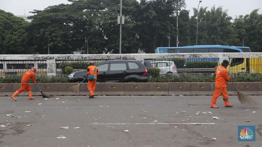Para pasukan orange membersihkan sampah yang berserakan di jalanan usai para pendemo membubarkan diri.