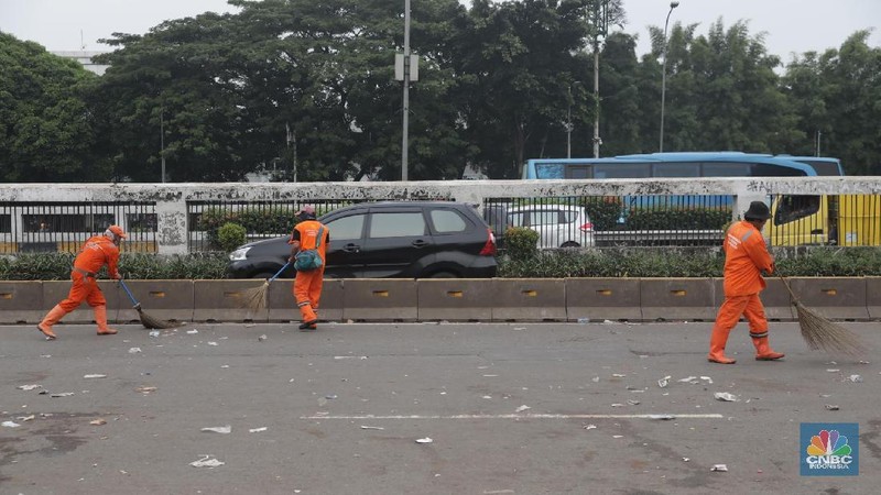 Para pasukan orange membersihkan sampah yang berserakan di jalanan usai para pendemo membubarkan diri.