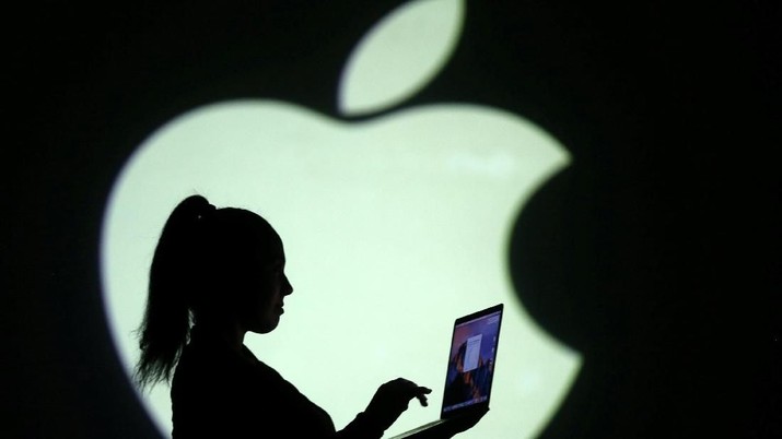 REFILE - CLARIFYING CAPTION Silhouette of laptop user is seen next to a screen projection of Apple logo in this picture illustration taken March 28, 2018.  REUTERS/Dado Ruvic