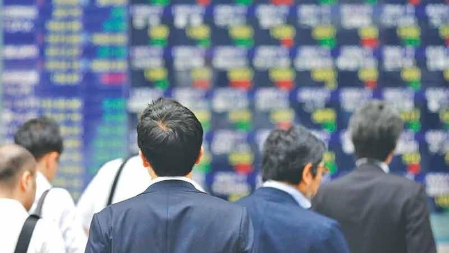 People walk past an electronic stock quotation board outside a brokerage in Tokyo, Japan.