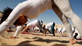 Semua peserta latihan yoga tak menggunakan alas kaki. Mereka berdiri, duduk, dan merundukkan tubuh di bawah terik sinar matahari.