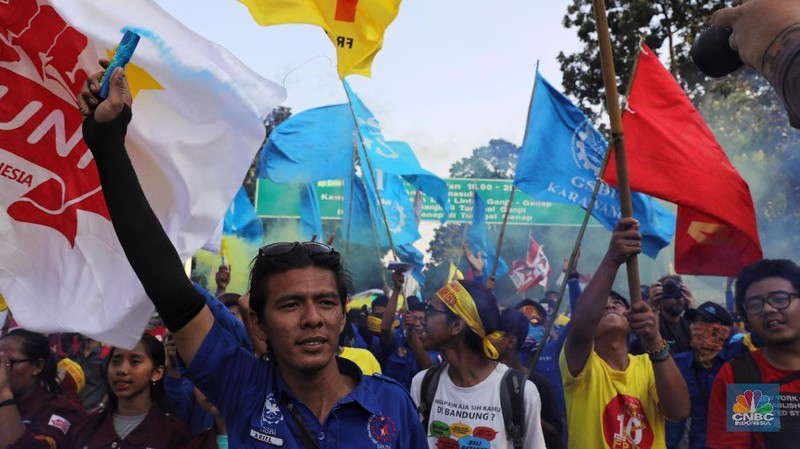 Massa dari berbagai aliansi buruh menyalakan flare atau gas asap sebelum membubarkan diri usai berorasi di depan Istana Negara, Jakarta.