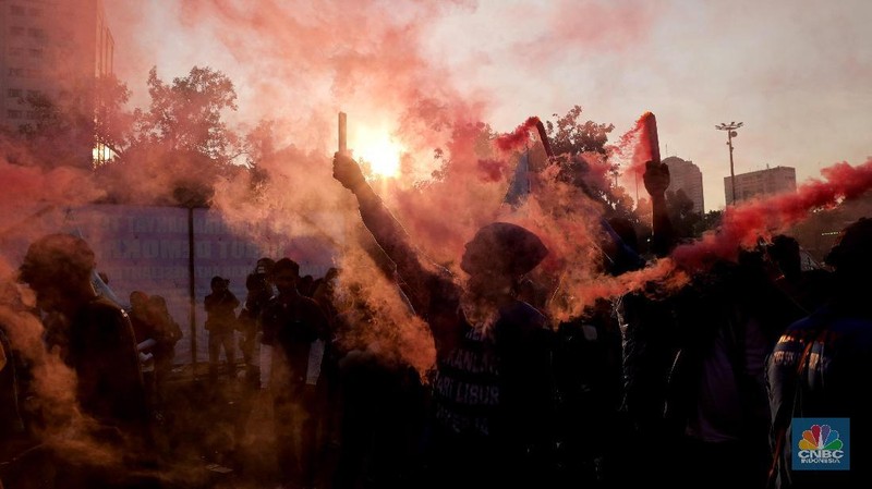 Massa dari berbagai aliansi buruh menyalakan flare atau gas asap sebelum membubarkan diri usai berorasi di depan Istana Negara, Jakarta.