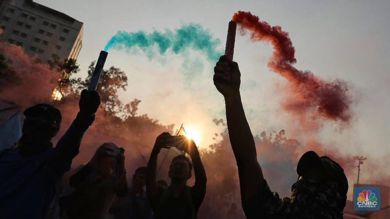 Massa dari berbagai aliansi buruh menyalakan flare atau gas asap sebelum membubarkan diri usai berorasi di depan Istana Negara, Jakarta.