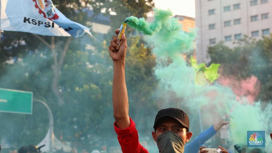 Massa dari berbagai aliansi buruh menyalakan flare atau gas asap sebelum membubarkan diri usai berorasi di depan Istana Negara, Jakarta.