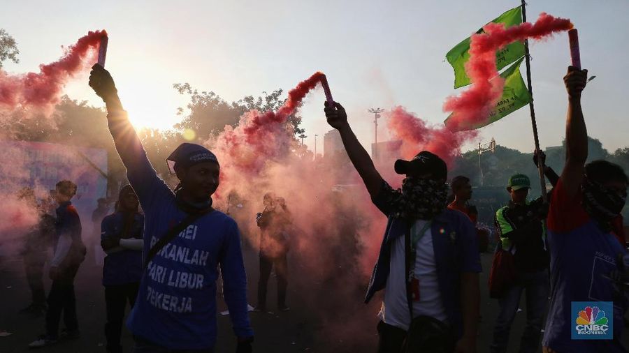 Massa dari berbagai aliansi buruh menyalakan flare atau gas asap sebelum membubarkan diri usai berorasi di depan Istana Negara, Jakarta.