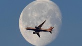 Pesawat komersial British Airways terbang melintasi bulan di atas kota London, Inggris. (Reuters/Toby Melville)