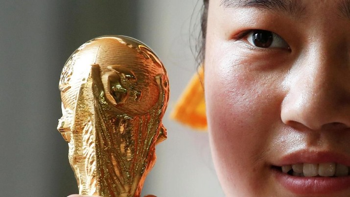 replika piala dunia Pekerja pengemasan Sun Mengwei, 20, dari provinsi Guizhou, berfoto dengan replika Piala Dunia FIFA 2018 yang diperkecil, terbuat dari paduan seng, di sebuah pabrik yang memproduksi produk berlisensi resmi di Dongguan, China 8 Mei 2018. Gambar diambil Mei 8, 2018. REUTERS / Bobby Yip