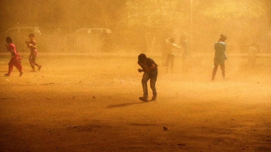 Children cover themselves during a dust storm in New Delhi, India May 13, 2018. REUTERS/Adnan Abidi