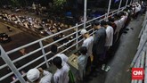 Deretan orang dalam susunan saf yang rapih di JPO Pasar Gembrong, Jakarta berupaya khusyuk menjalankan salat tarawih di antara suasana jalanan dan kendaraan yang riuh. (CNN Indonesia/Adhi Wicaksono)