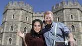 Sepasang pengunjung mengenakan topeng Pangeran Harry dan Meghan Markle di depan Kastel Windsor yang akan menjadi lokasi pernikahan anggota kerajaan itu pada 19 Mei nanti. (Reuters/Marko Djurica)
