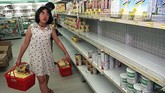 Seorang pelanggan berjalan melewati rak-rak kosong yang biasanya terisi dengan produk olahan susu di sebuah supermarket di Jakarta. Inflasi yang mencapai 60 persen pada 1998 membuat toko-toko di Jakarta kehabisan bahan makanan. (AFP PHOTO Kemal JUFRI)
