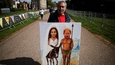 Kaya Mar, warga London sampai membawa lukisannya untuk berpose di Windsor. Menurutnya, pernikahan Harry Markle bisa membuat warga Inggris lupa sejenak pada berbagai masalah mereka, seperti Brexit. (REUTERS/Damir Sagolj)