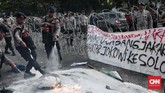 Polisi berupaya memadamkan api yang membakar ban yang dibawa para mahasiswa pelaku aksi Refleksi 20 tahun Reformasi. (CNN Indonesia/Andry Novelino)