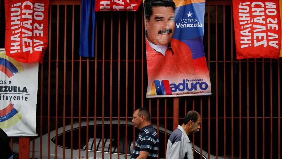 Men walk past campaign posters of Venezuela's President Nicolas Maduro in Caracas, Venezuela May 8, 2018. Picture taken May 8, 2018. REUTERS/Adriana Loureiro
