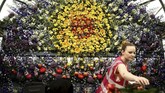 Seorang pekerja terlihat menyusun rangkaian bunga yang dipanjang dengan konsep instalasi beraneka bentuk di RHS Chelsea Flower Show 2018. (REUTERS/Simon Dawson)