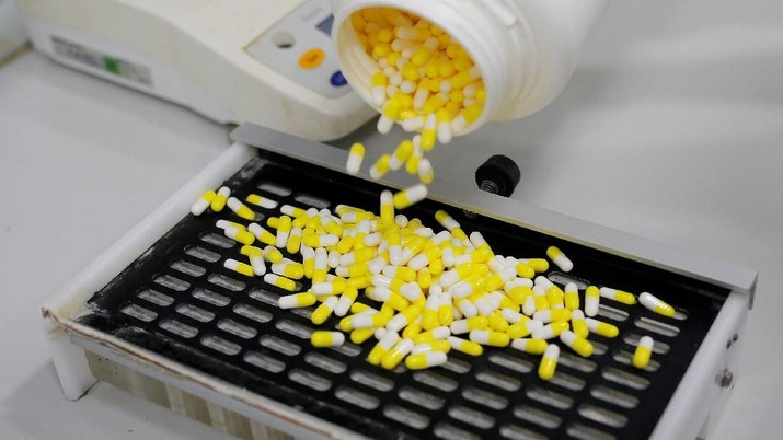 A laboratory technician places medication capsules on a capsules counter during packaging in a laboratory at 
