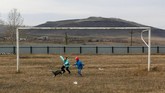 Dua orang bocah bermain boneka di sebuah lapangan daerah Novosyolovo, Krasnoyarsk. (REUTERS/ Ilya Naymushin)