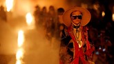 Seperti berada di sebuah setting film horor, runway dipenuhi lilin katedral dan asap yang memenuhi udara saat para tamu mengambil tempat duduk mereka di tengah kegelapan. (REUTERS/Jean-Paul Pelissier)