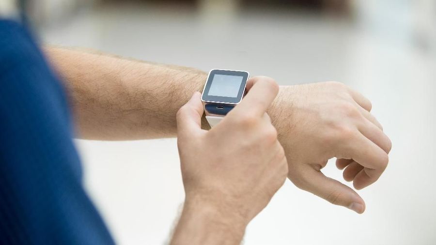 Close-up of hand of young man touching display on his smart watch with blank black screen, using internet, messaging, making call, or using app