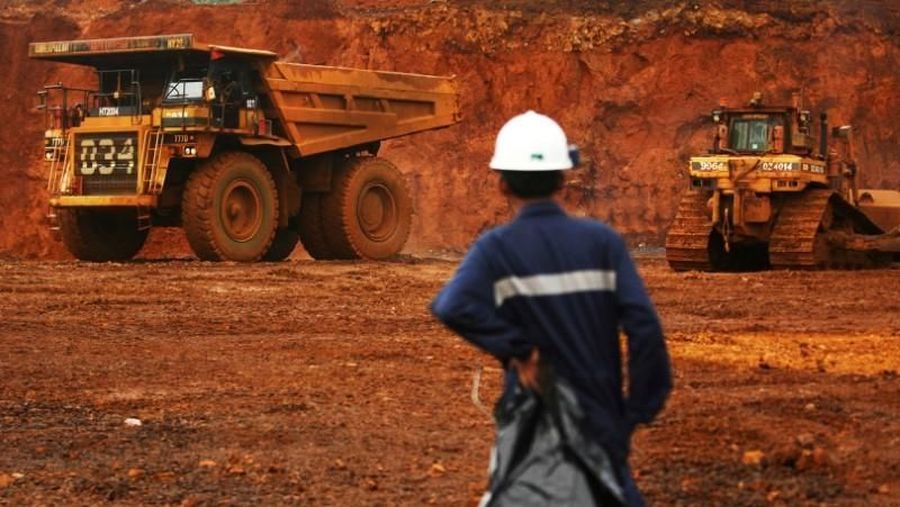 A worker watches as trucks load up raw nickel near Sorowako, Indonesia's Sulawesi island, January 8, 2014. REUTERS/Yusuf Ahmad