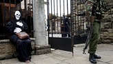 Di luar gedung parlemen di Nairobi, Kenya, seorang polisi berjaga-jaga dekat seorang aktivis lingkungan yang mengenakan kostum. Aktivis itu memprotes rencana pembangunan pabrik batu bara. (Reuters/Baz Ratner)